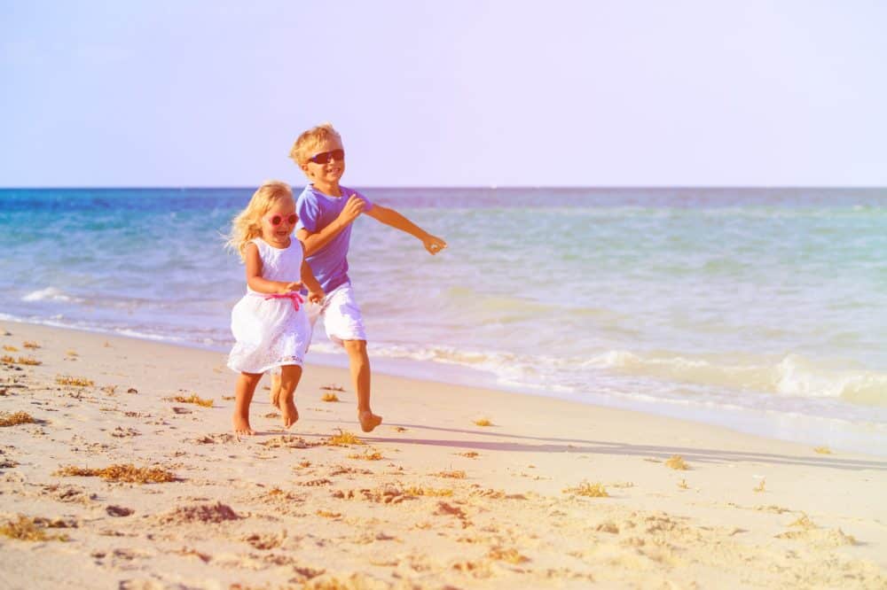 chłopiec i dziewczynka biegające na plaży, wakacje rodzinne