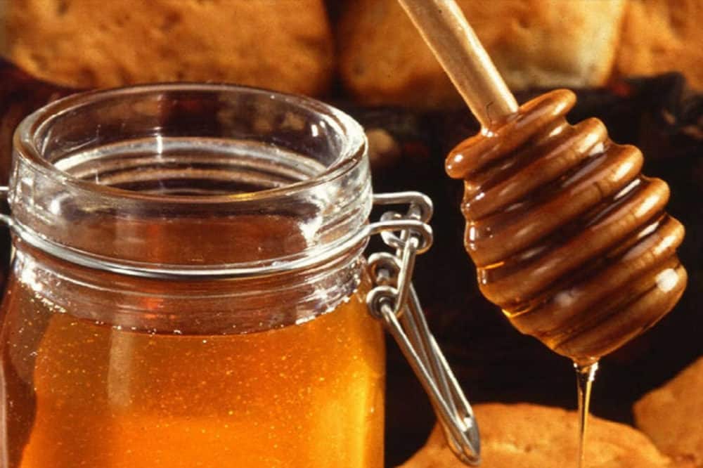 Słoik miodu z łyżką drewnianą