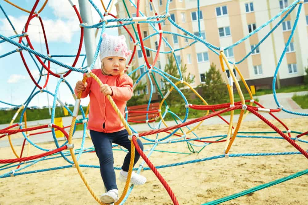 Dziewczynka wspina się na placu zabaw.