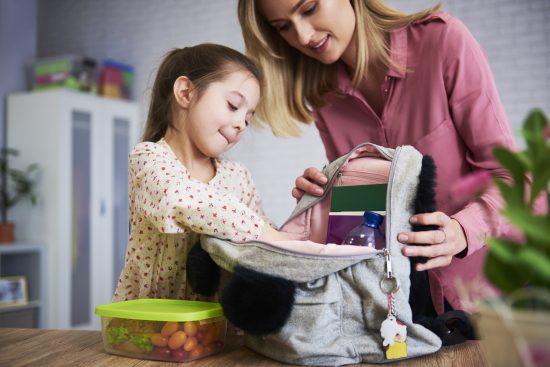 Młoda mama i córka pakują plecak do szkoły