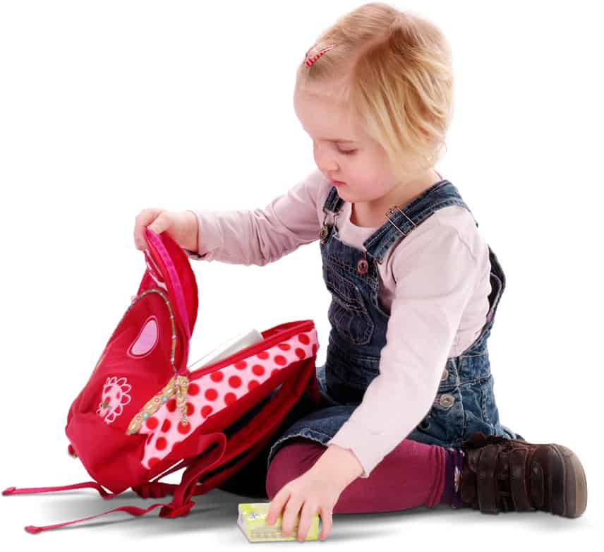 Dziewczynka z plecakiem. Pakuje różowy plecak do przedszkola.