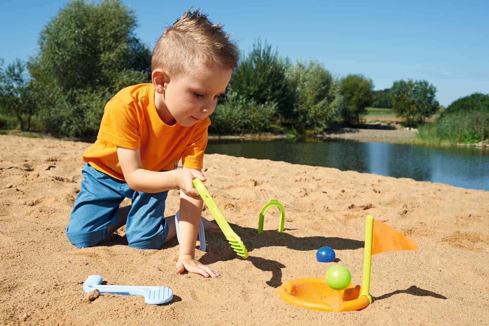 Chłopczyk bawi się w golfie na plaży, zabawka marki Haba.